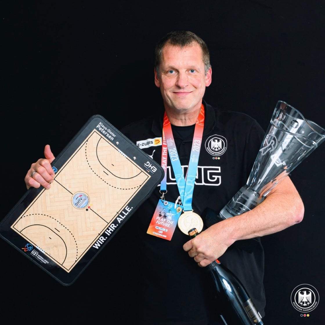 Handball-Taktikboard als Zeichentafel, Mann hält Brett und Pokal bei Preisverleihung.