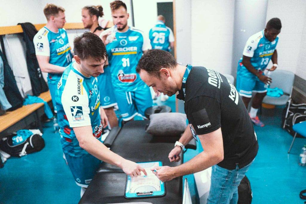 Handball-Taktikboard auf dem Tisch, Trainer zeigt Markierungen während einer Besprechung.